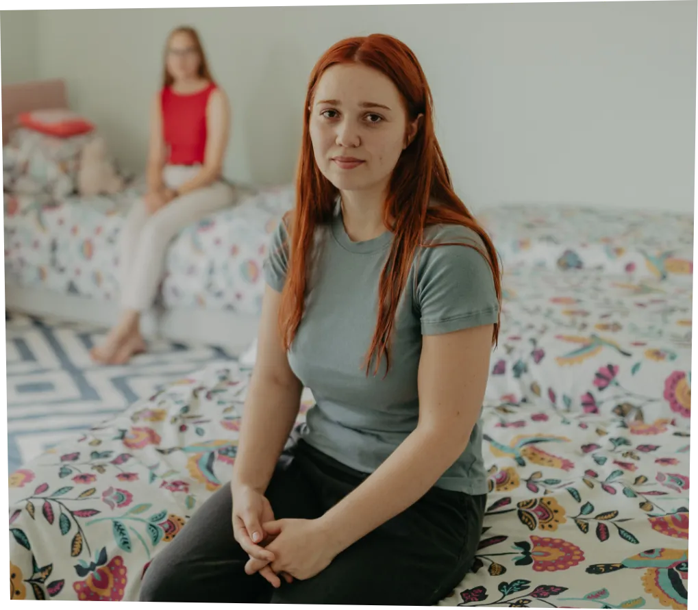 A teenage girl sitting on a bed in a family home